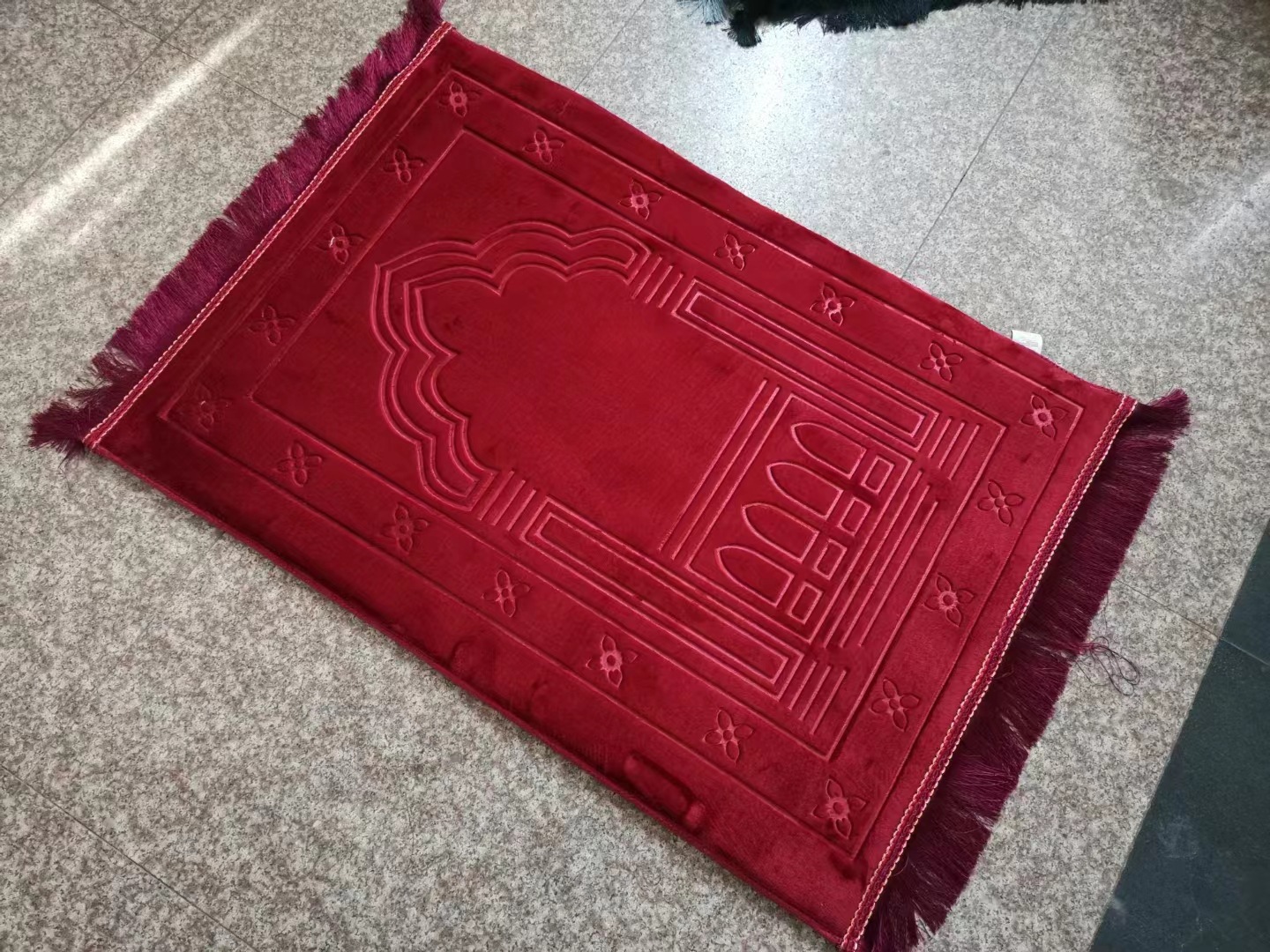 Thick padded red prayer mat 80x120 cm laid on the floor Thick padded red prayer mat 80x120 cm laid on the floor
